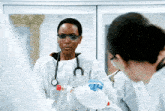 a female doctor wearing goggles and a stethoscope holds a bottle