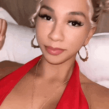 a woman in a red top and hoop earrings is sitting on a bed .