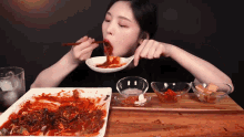 a woman is eating a plate of food with chopsticks and a spoon
