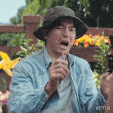 a man wearing a hat and a denim shirt has a netflix logo on the bottom