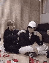 a group of young men are sitting on the floor in a living room with coca cola cans .