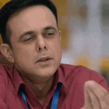 a man in a red shirt with a blue lanyard around his neck is making a face