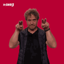 a man making a peace sign in front of a red background with swr3