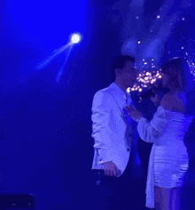 a man and a woman are standing next to each other on a stage .