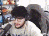 a man wearing glasses and headphones is sitting in front of a microphone in a room .