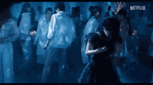 a woman in a black dress is dancing with a man in a white shirt in a crowded dance floor .