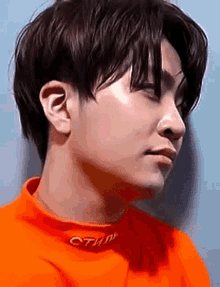 a close up of a person 's face wearing an orange sweater .