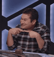 a man in a plaid shirt is pointing at something with his fingers