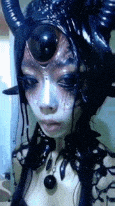 a close up of a woman 's face with horns on her head
