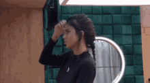 a woman in a black shirt adjusts her braided hair