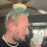 a man with blue hair is holding twenty dollar bills in his hand