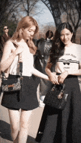 a woman wearing a christian dior t-shirt is holding another woman 's hand