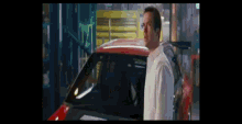 a man standing in front of a red car with the door open