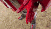 a close up of a red robot standing on top of a field of dry grass .