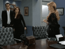 a man and two women are standing in a room