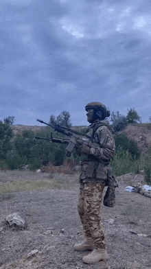 a soldier is standing in the dirt holding a rifle .