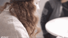 a woman with red curly hair is looking at herself in a mirror with gifsdayrol written below her