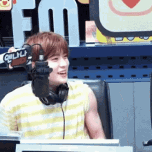 a young man wearing headphones is smiling in front of a microphone with the word fm in the background