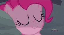 pinkie pie is sleeping in a bed with her eyes closed .
