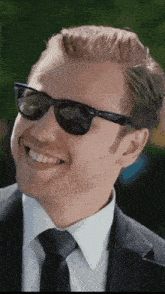 a man in a suit and tie is wearing sunglasses