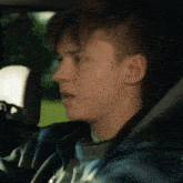 a close up of a young man 's face while driving a car