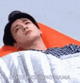 a man is laying in a bed with a pillow and a blanket .