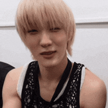 a woman with blonde hair is wearing a black tank top and a lanyard around her neck