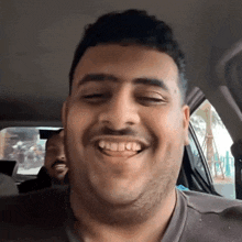 a man with a beard is smiling while sitting in the back seat of a car