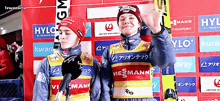 two athletes are standing in front of a wall with advertisements for hylo and viezmann