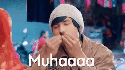 a man wearing a beanie is blowing a bubble with the word muhaaaa on the bottom