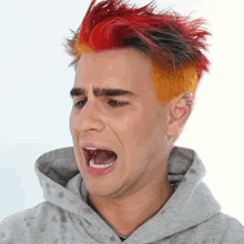 a man with red and orange hair is wearing a hoodie