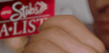 a close up of a person holding a stubs a-list sticker