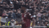 a soccer player wearing a kappa jersey is running on a field in front of a crowd
