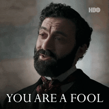 a man with a beard says " you are a fool " in front of him