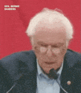 sen. bernie sanders is giving a speech in front of a microphone .
