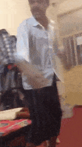 a man in a blue shirt and black shorts is dancing in a room