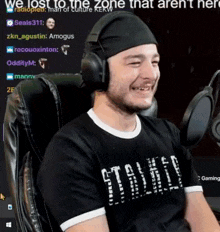 a man wearing headphones and a shirt that says " we lost to the zone that aren 't here " is smiling