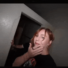 a woman is being held by a man in a dark room while looking at the camera .