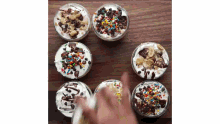 a person is pouring whipped cream on top of a dessert with sprinkles and chocolate chips .