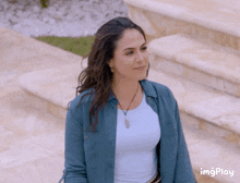 a woman wearing a white shirt and a blue shirt is standing in front of some stairs ..
