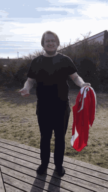 a man wearing a black shirt is holding a red and white flag