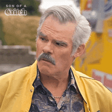 a man with a mustache wearing a yellow jacket