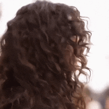 a close up of a woman 's curly hair with a blurred background .