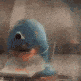a blue toy dolphin is sitting on a table with a cd in its mouth