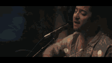 a man is singing into a microphone while playing a guitar