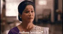 a woman in a purple top and white saree says ardham ayindaa