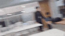 a blurry picture of a person standing next to a table in a room .
