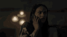 a woman is talking on a cell phone in a dark room and making a funny face .