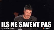 a man in a suit stands in front of a microphone with the words ils ne savent pas behind him