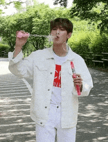 a young man is blowing soap bubbles in a park .